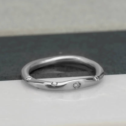 Organic, irregular shaped ring in 10 karat recycled white gold with a satin finish, flush set with 8 1.2mm colourless diamonds.