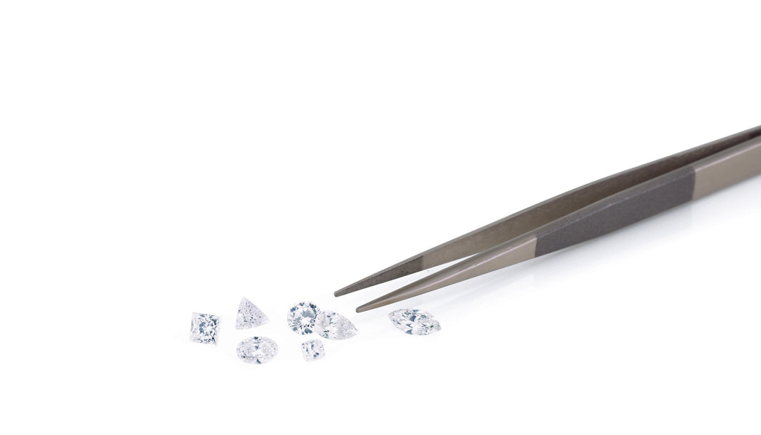 a pair of tweezers and a variety of tiny diamonds