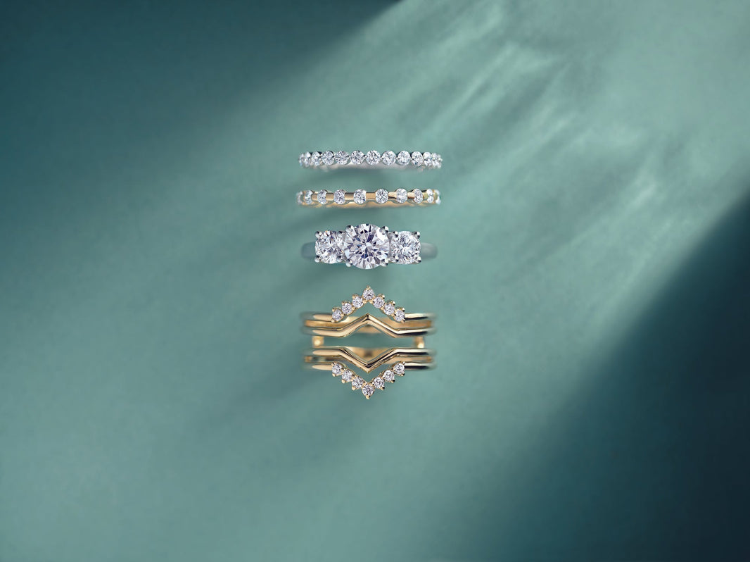 A selection of 4 Malleable diamond rings on a green background