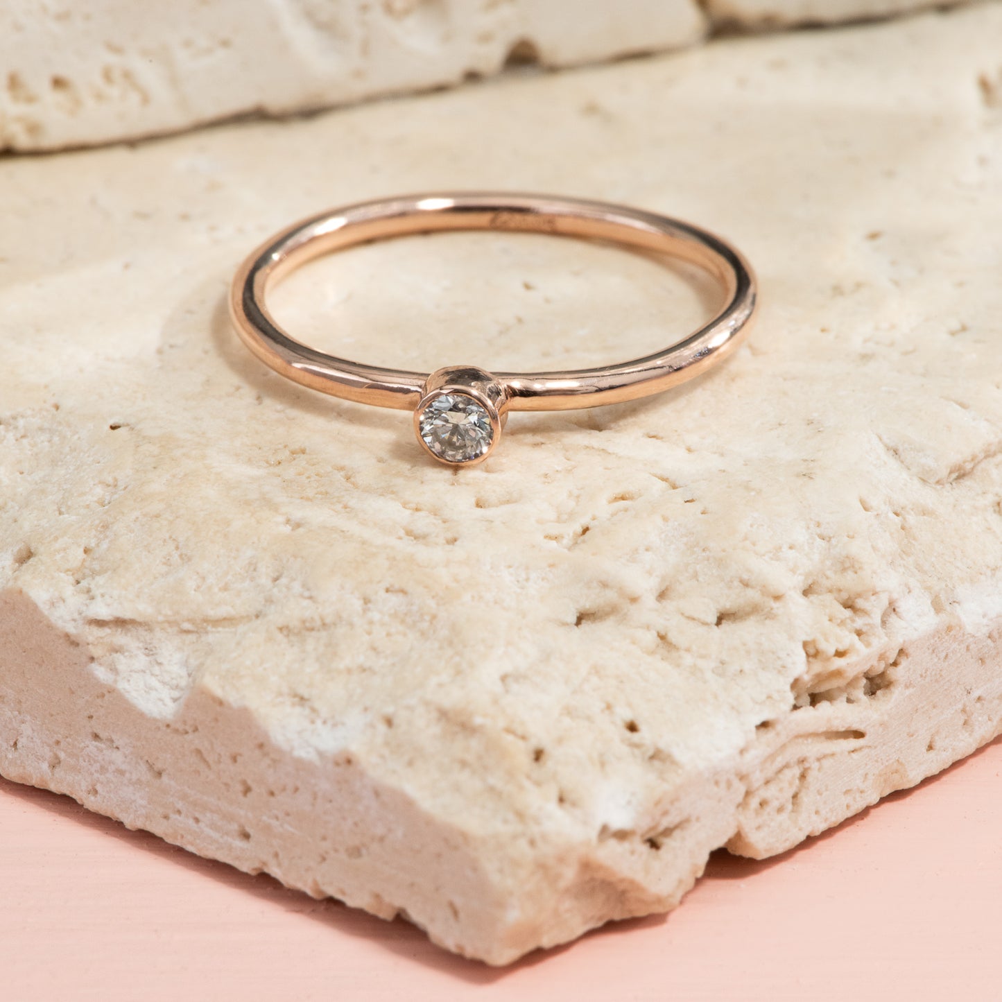 Highly polished rose gold ring with one bezel set diamond.