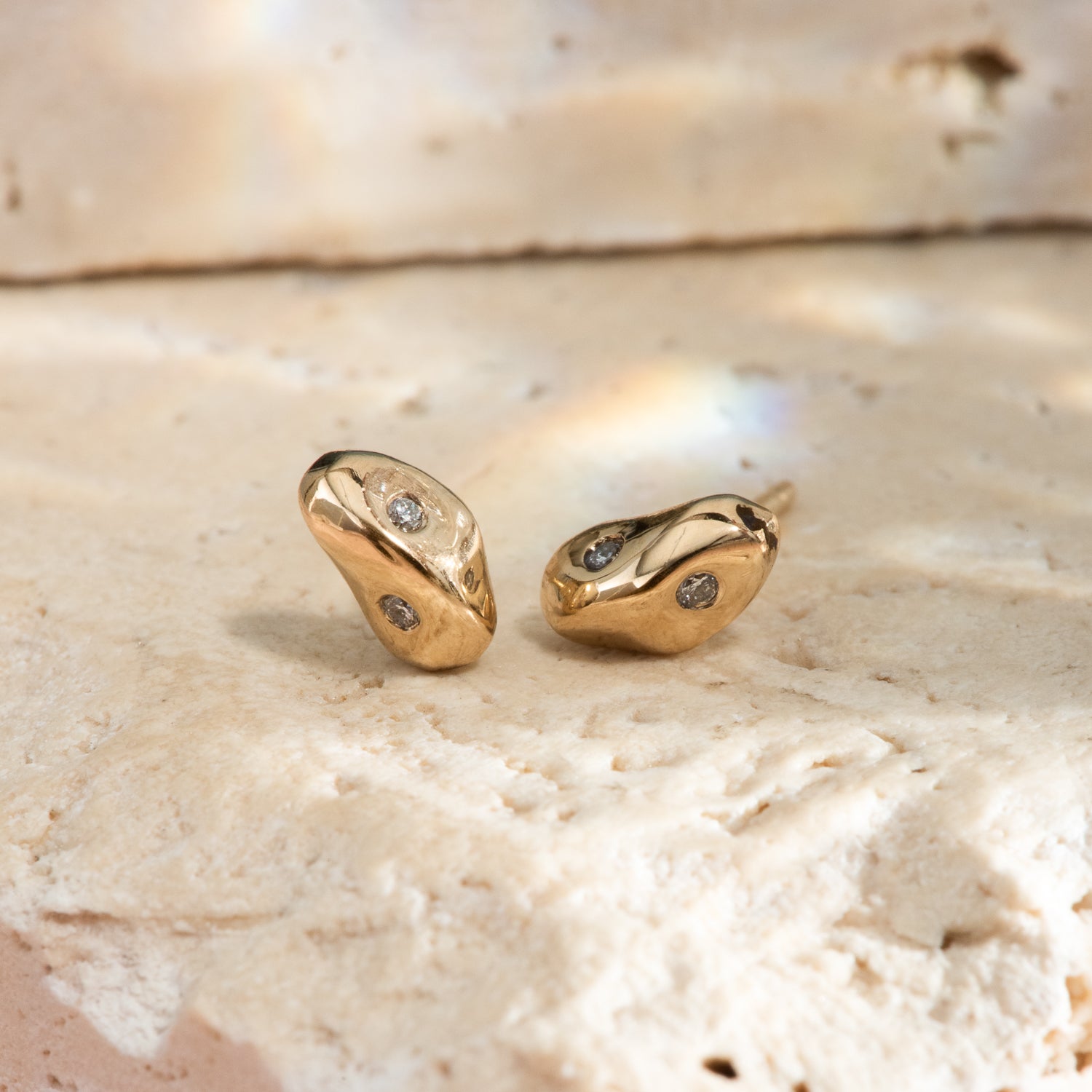 Irregular, pebble shaped yellow gold stud earrings, each with 2 flush set small diamonds.