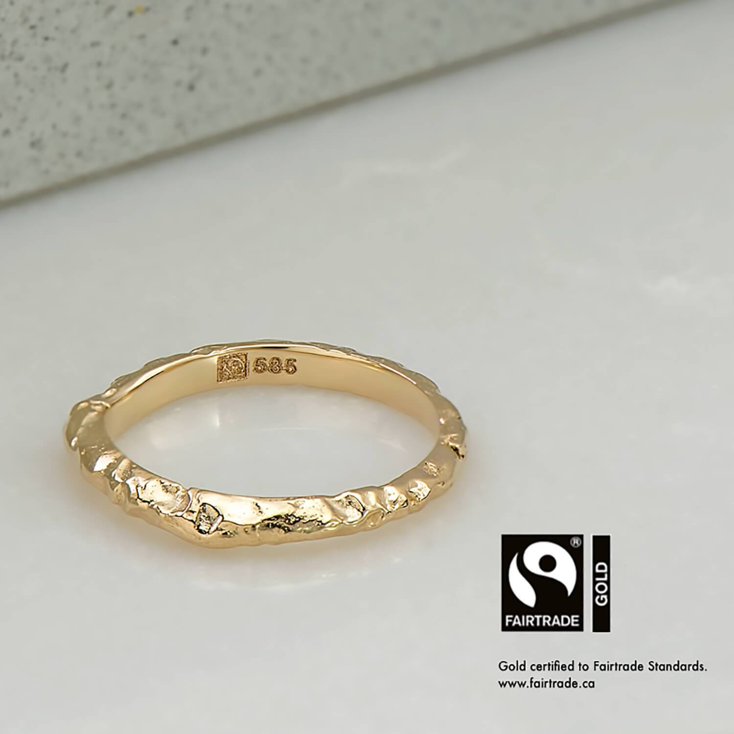 14 karat Fairtrade Certified yellow gold wedding ring with a with a cathedral profile and baroque carved surace. The ring is engraved with the Fairtrade logo and hallmarked 585.