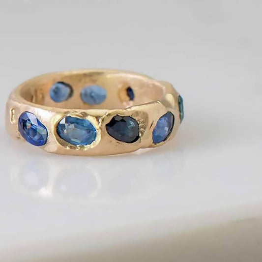 Recycled 14 karat yellow gold wedding ring in which contains 10 natural blue sapphires with a total weight of 2.75 carats in which have been set in cast. The width is 5mm with a thickness of 1.8mm