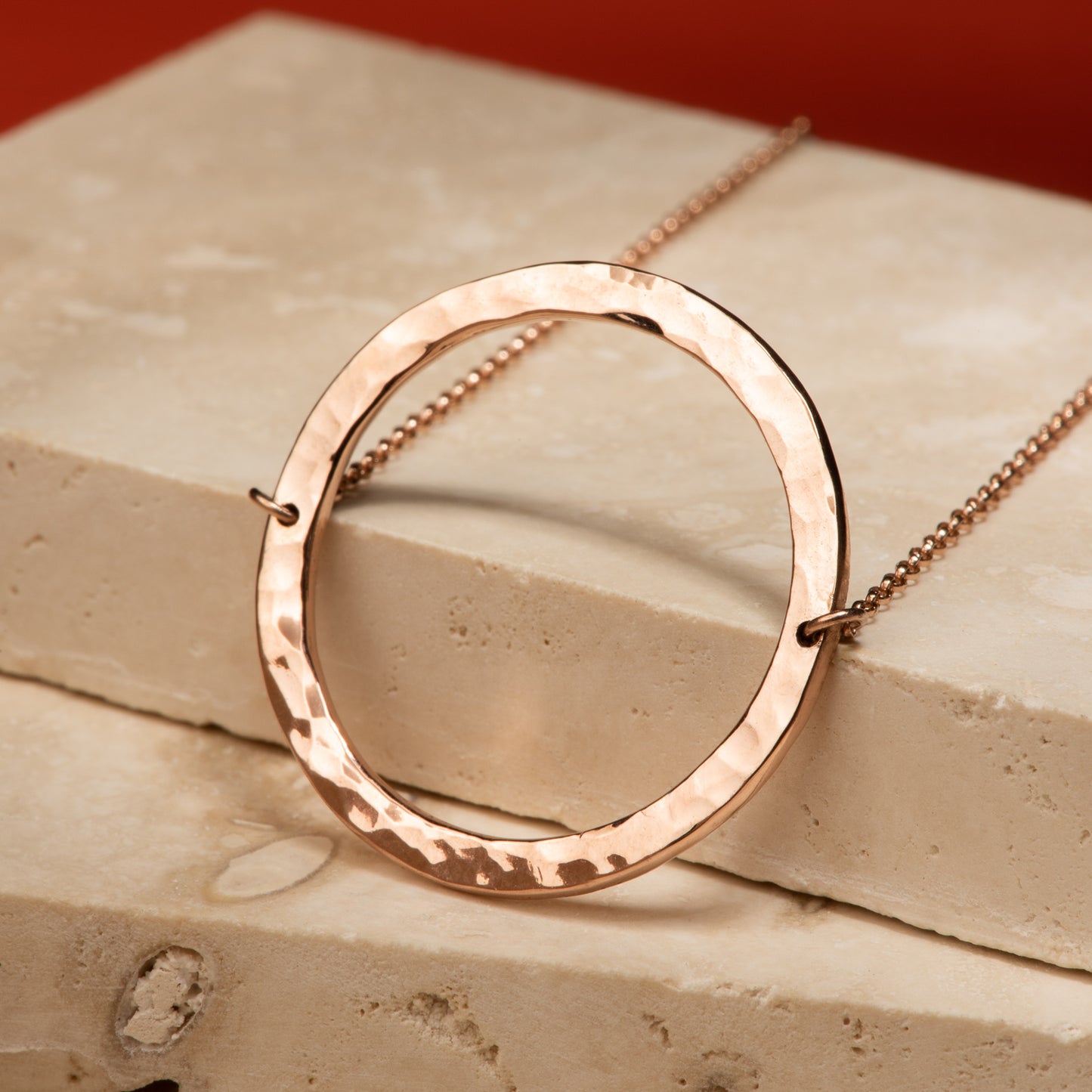 2.5 centimetre wide circular 10 karat recycled rose gold pendant with a hammer finish, attached to a 19" rolo chain.
