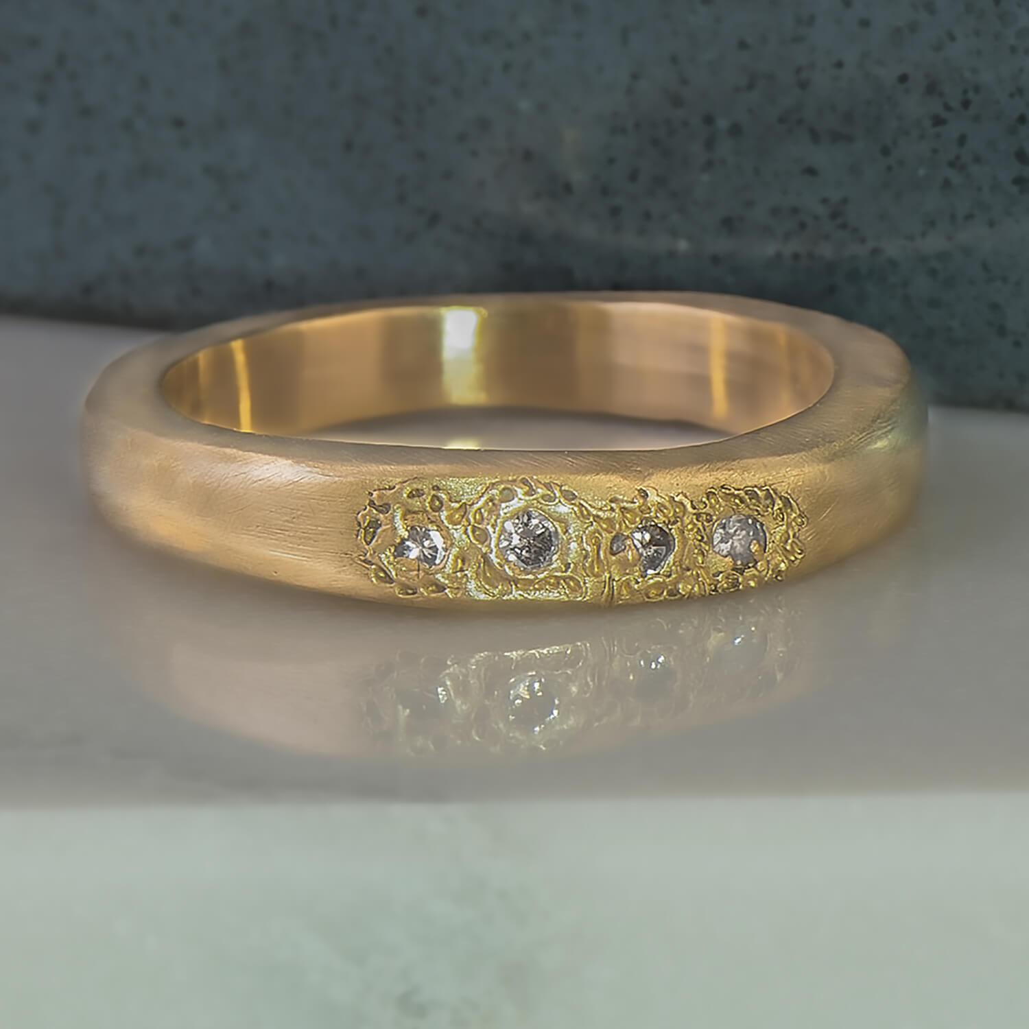 Recycled 14 karat yellow gold satin finished signet ring. The band is an irregular rectangular shape housing four, 2mm natural blue sapphires in which have been set in cast.