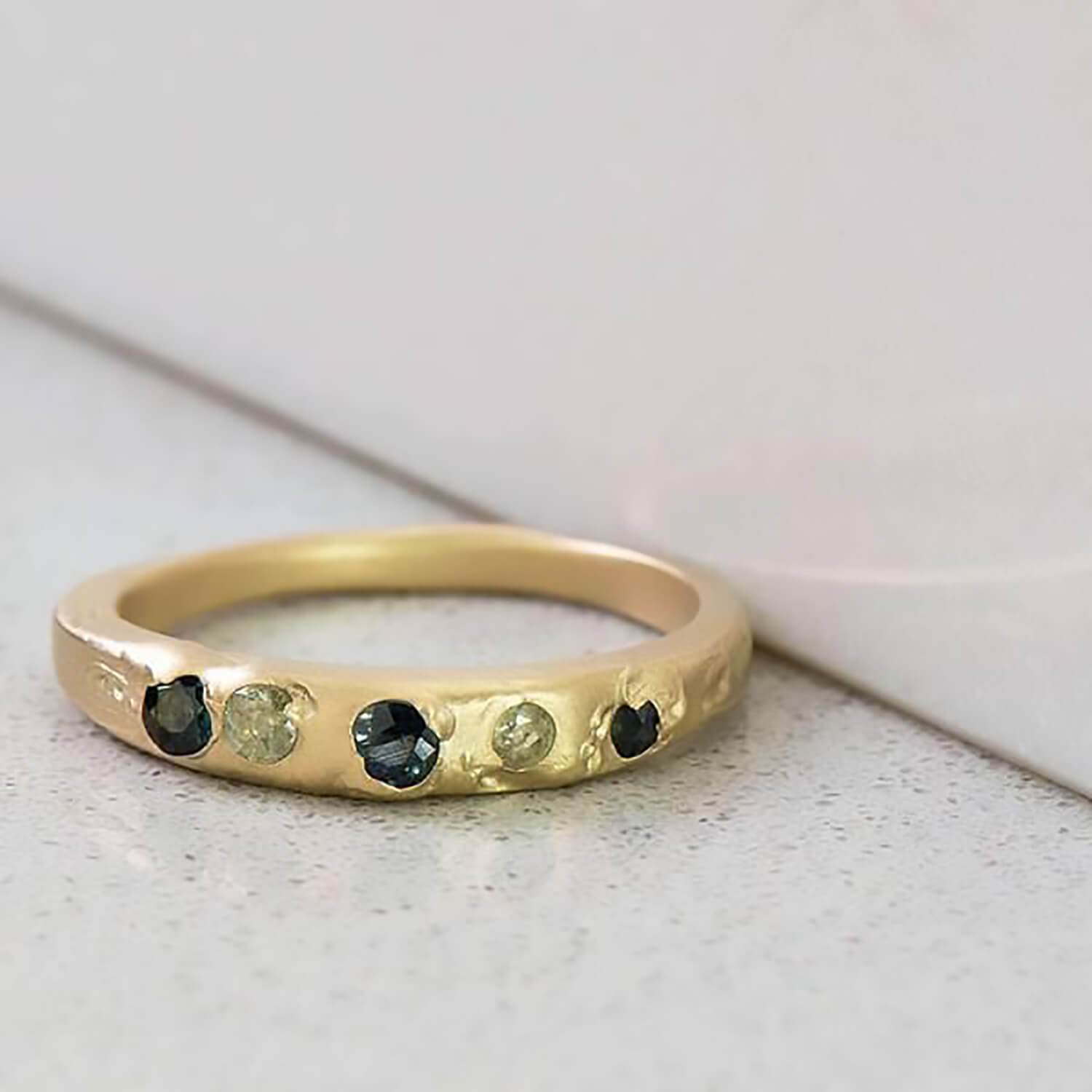 Recycled 14 karat yellow gold set in cast Kimberlite ring with five natural recycled sapphires brought to a satin finish.