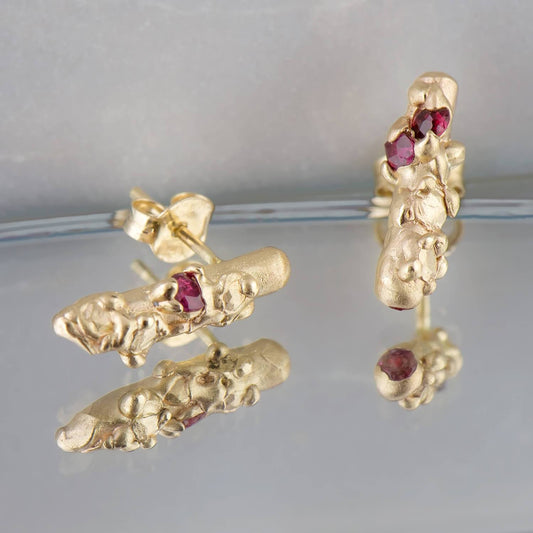 14 karat recycled yellow gold with 4 recycled rubies in which have been set in cast. The studs have a globular tubular profile with a luxe satin sheen measuring 14mm in length & 3mm in diameter