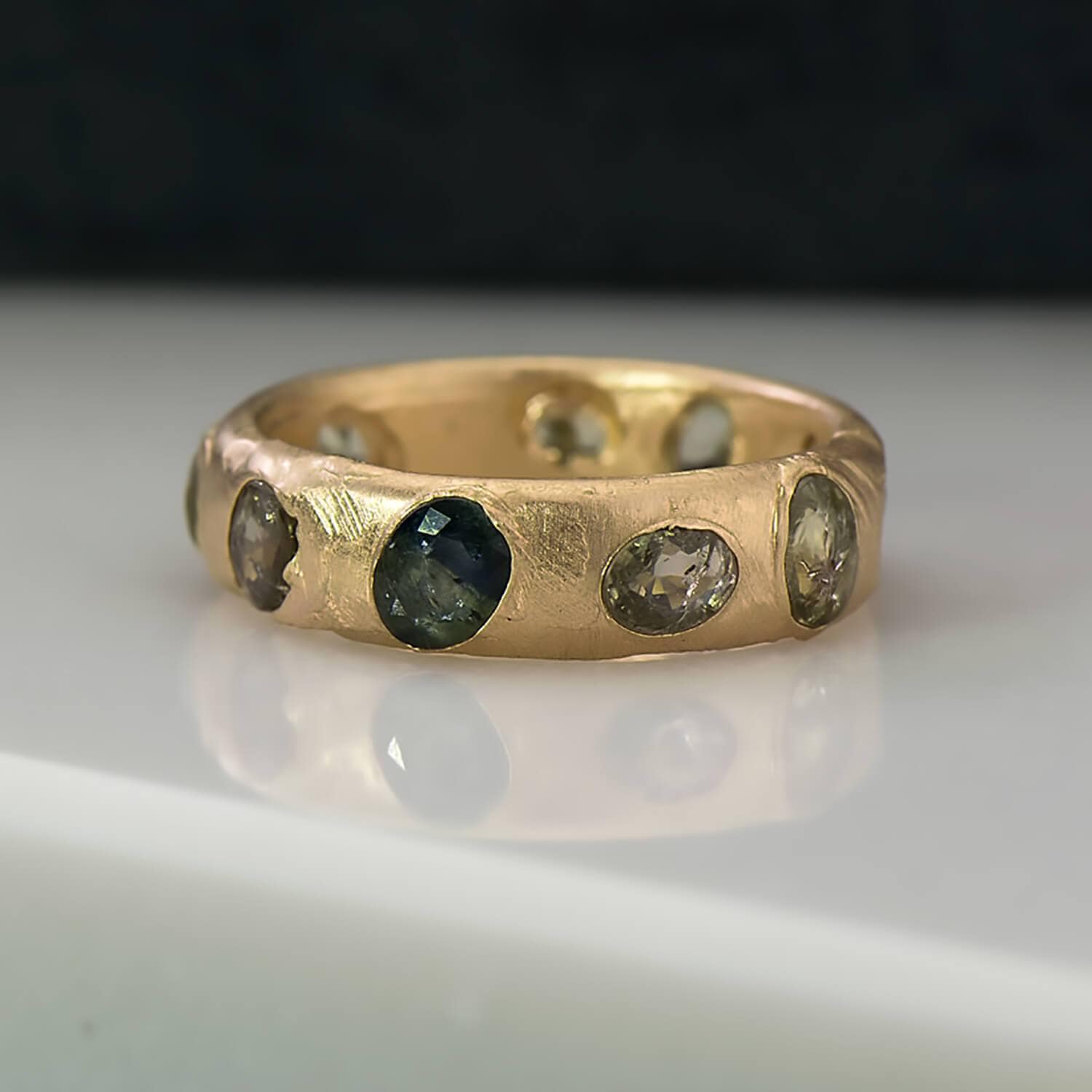 Recycled 14 karat yellow gold wedding ring with  10 recycled natural green sapphires in which have been set in cast. The band is has a luxe sheen with the width being 5mm and the thickness, 1.8mm