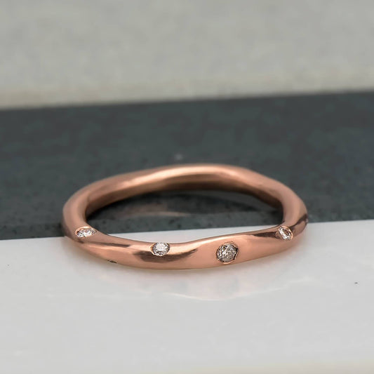 Organic, irregular shaped ring in 10 karat recycled rose gold with a satin finish, flush set with 8 1.2mm colourless diamonds.