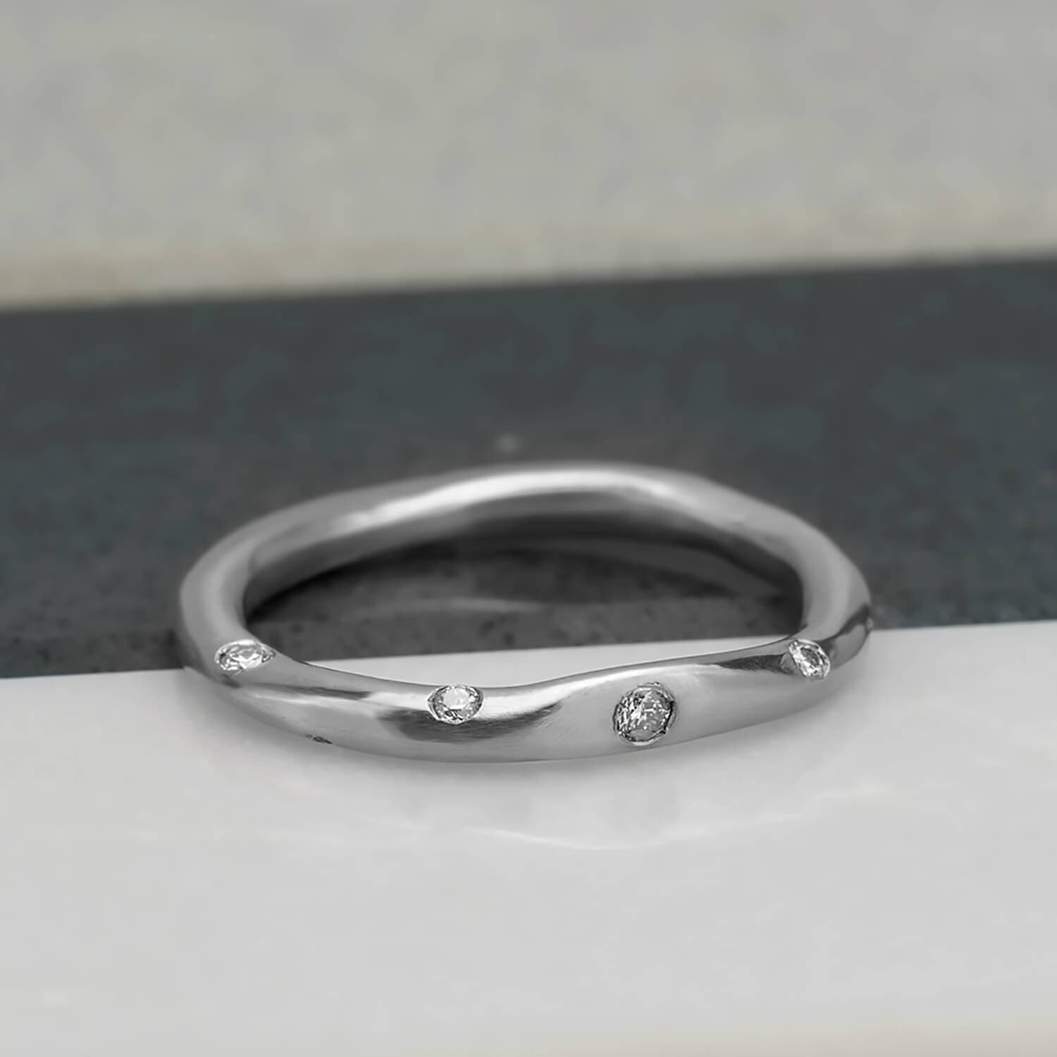 Organic, irregular shaped ring in 10 karat recycled white gold with a satin finish, flush set with 8 1.2mm colourless diamonds.
