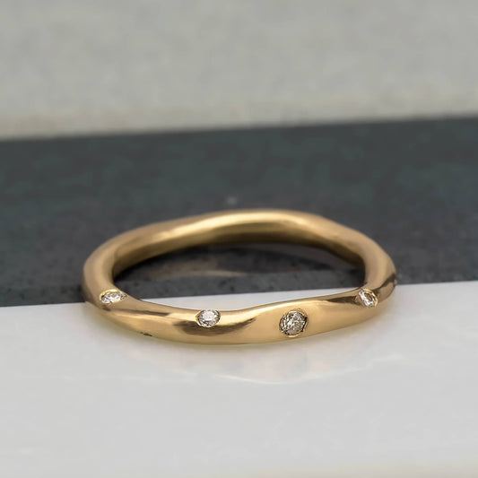 Organic, irregular shaped ring in 10 karat recycled yellow gold with a satin finish, flush set with 8 1.2mm colourless diamonds.
