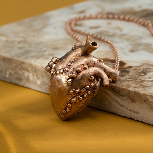 An anatomical heart locket, in rose gold, set with several rubies and diamonds.
