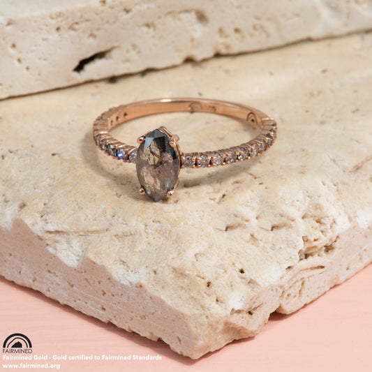 Small grey diamonds go around a rose gold band, with a centre salt and pepper diamond in a marquise cut.
