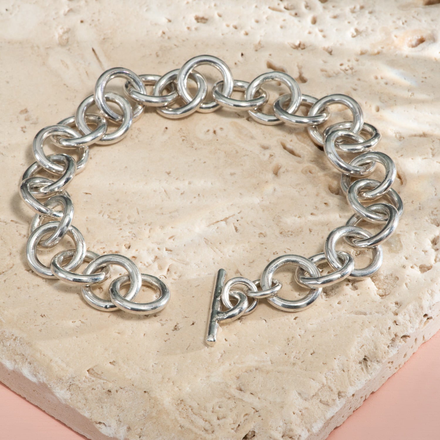 Large, polished circular links of silver form a chain bracelet with a toggle closure.