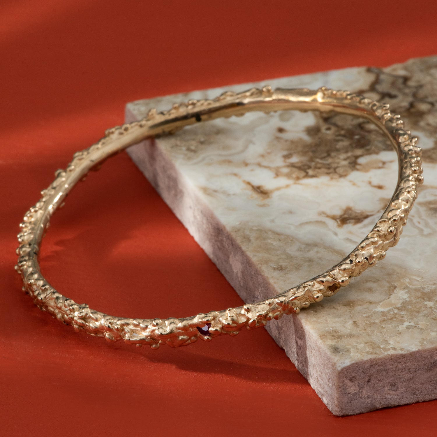 Small bubbles of yellow gold flow all the way around a polished bangle.
