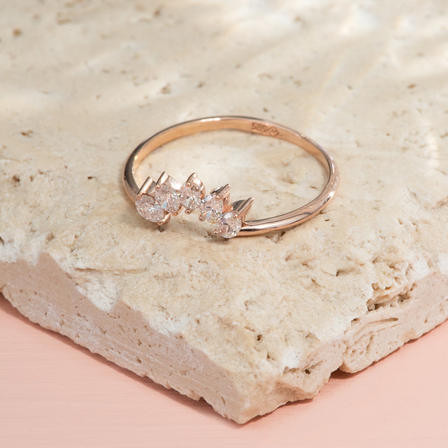 A half round polished rose gold band with 5 oval diamonds set in a rounded chevron.