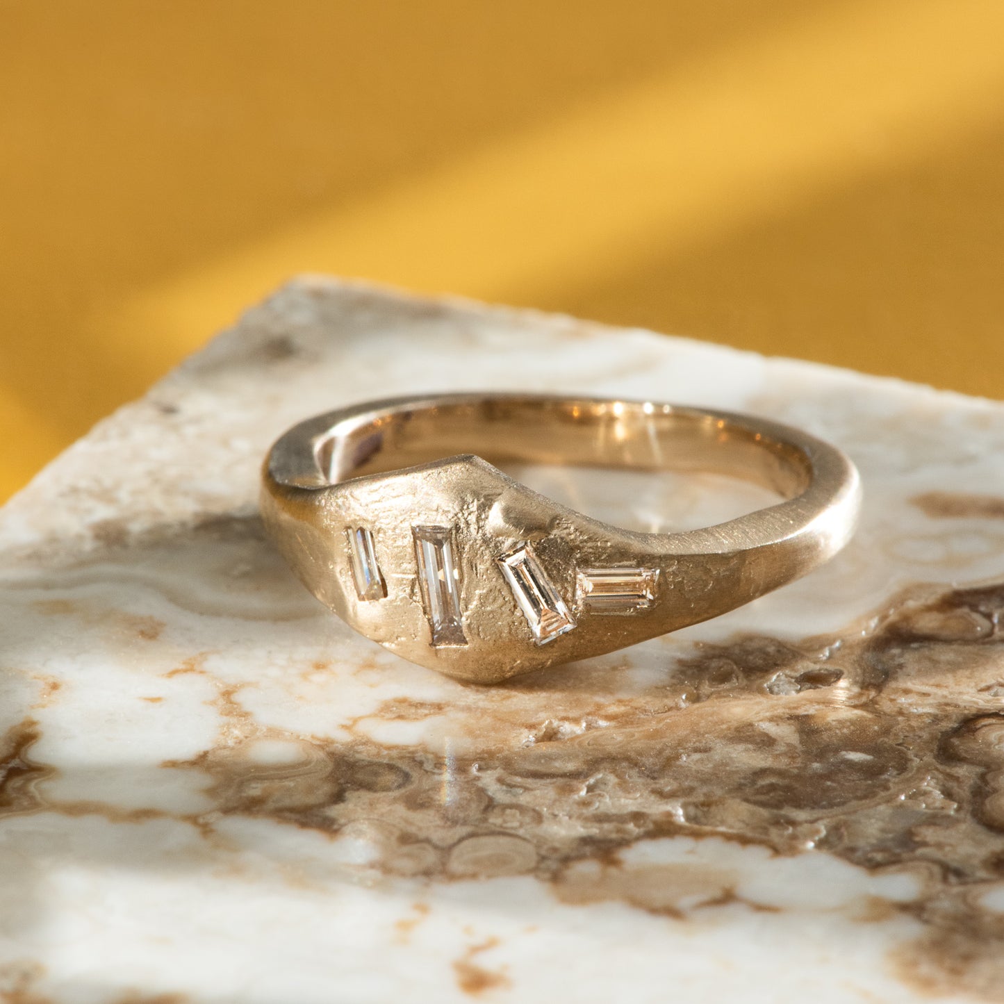 4 baguette diamonds asymmetrically posed and flush set in a yellow gold signet ring.