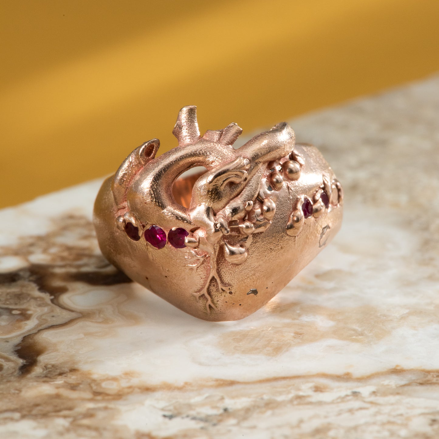 Anatomical heart on a thick band of rose gold, set with pink & red sapphires, and diamonds.