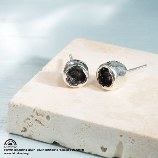 A small pair of silver studs, with an oxidized cup with a rim of polished silver.