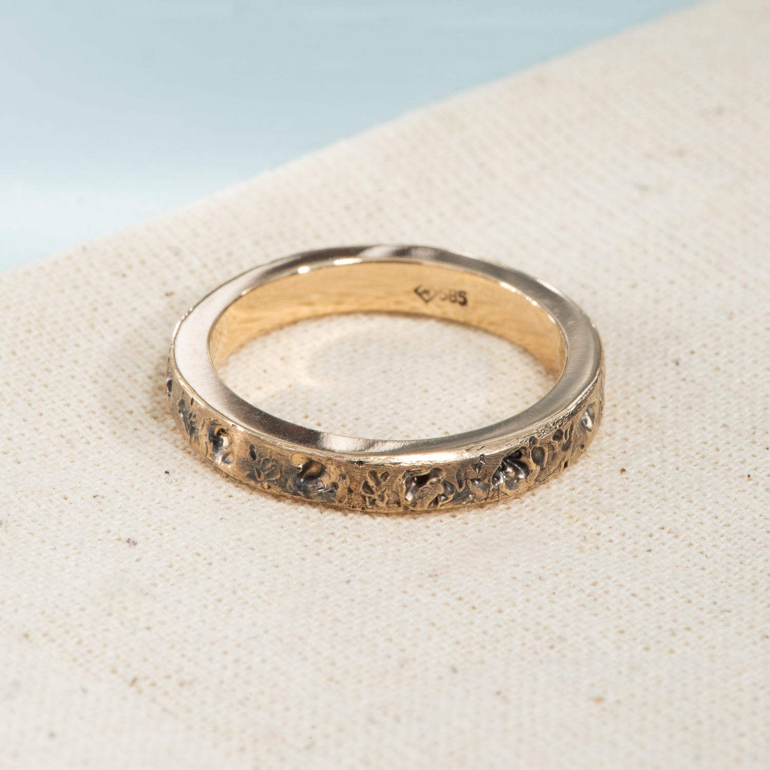 A lightly oxidized yellow gold band with a pitted, textured finish.