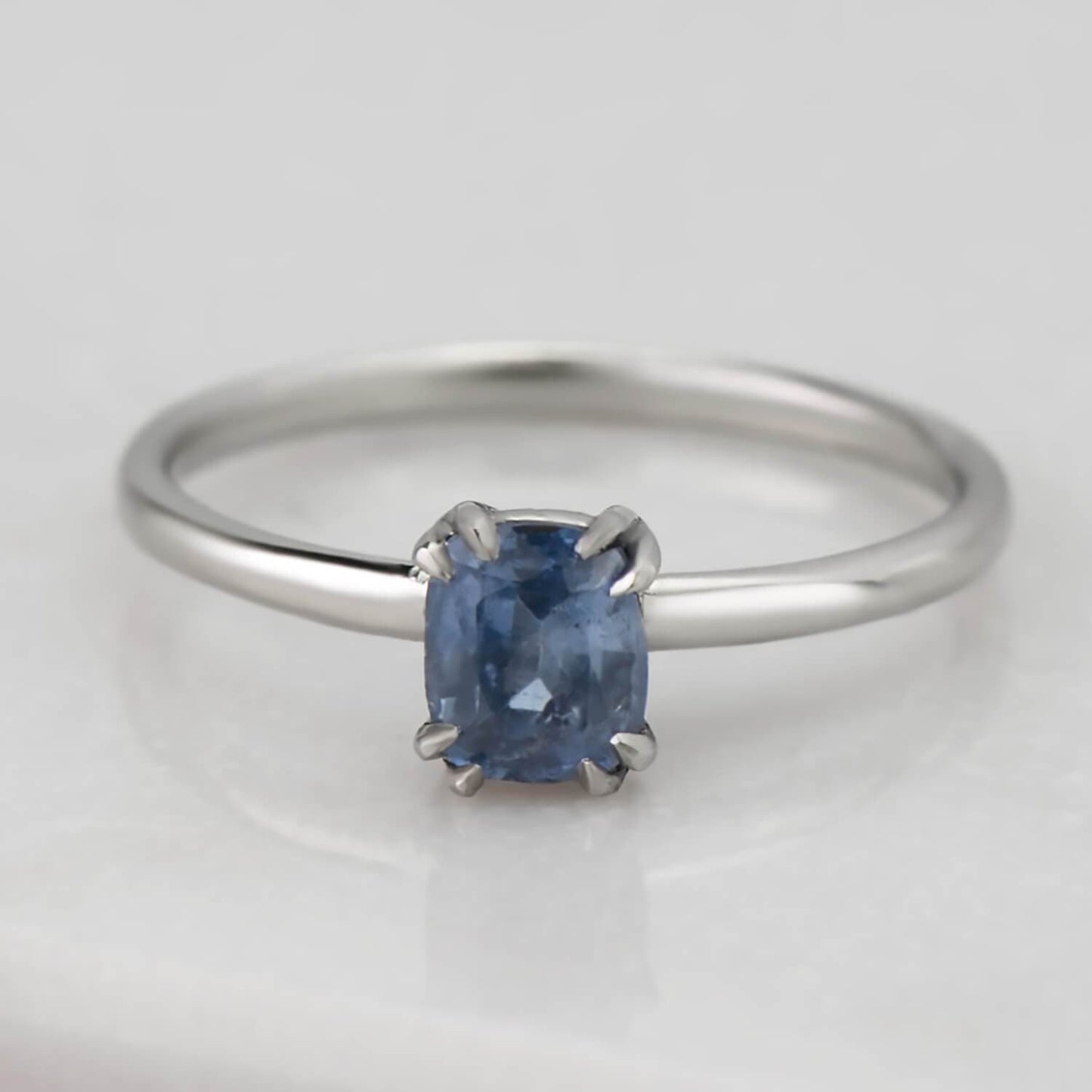Recycled 14 karat white gold solitaire sapphire ring. The band is 1.80mm in width and 1.2mm in thickness, in an eight prong setting it houses a 0.41 carat natural blue cushion cut sapphire