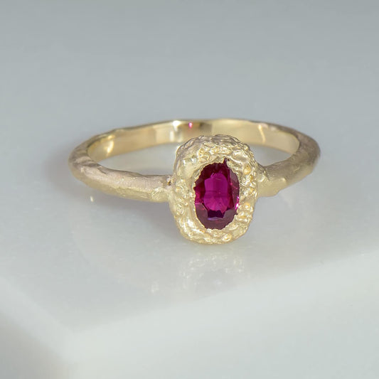 Handmade in 14 karat recycled yellow gold using a set in cast 0.52 carat natural pink oval sapphire. The head of the ring has a pitted texture whilst the shank has an overlapping, rich aesthetic.
