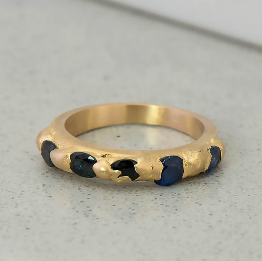 14 karat yellow gold set in cast ring with 5 natural blue recycled sapphires with a total weight of 1.25 carats. The band is 3mm in width tapered down to 2.5mm at the base of the shank.