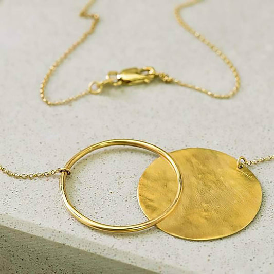 14 karat recycled yellow gold ripple necklace containing a 1mm thick disc in which has been textured to a ripple affect and a 25mm ring attached with a 19" yellow gold rolo chain.
